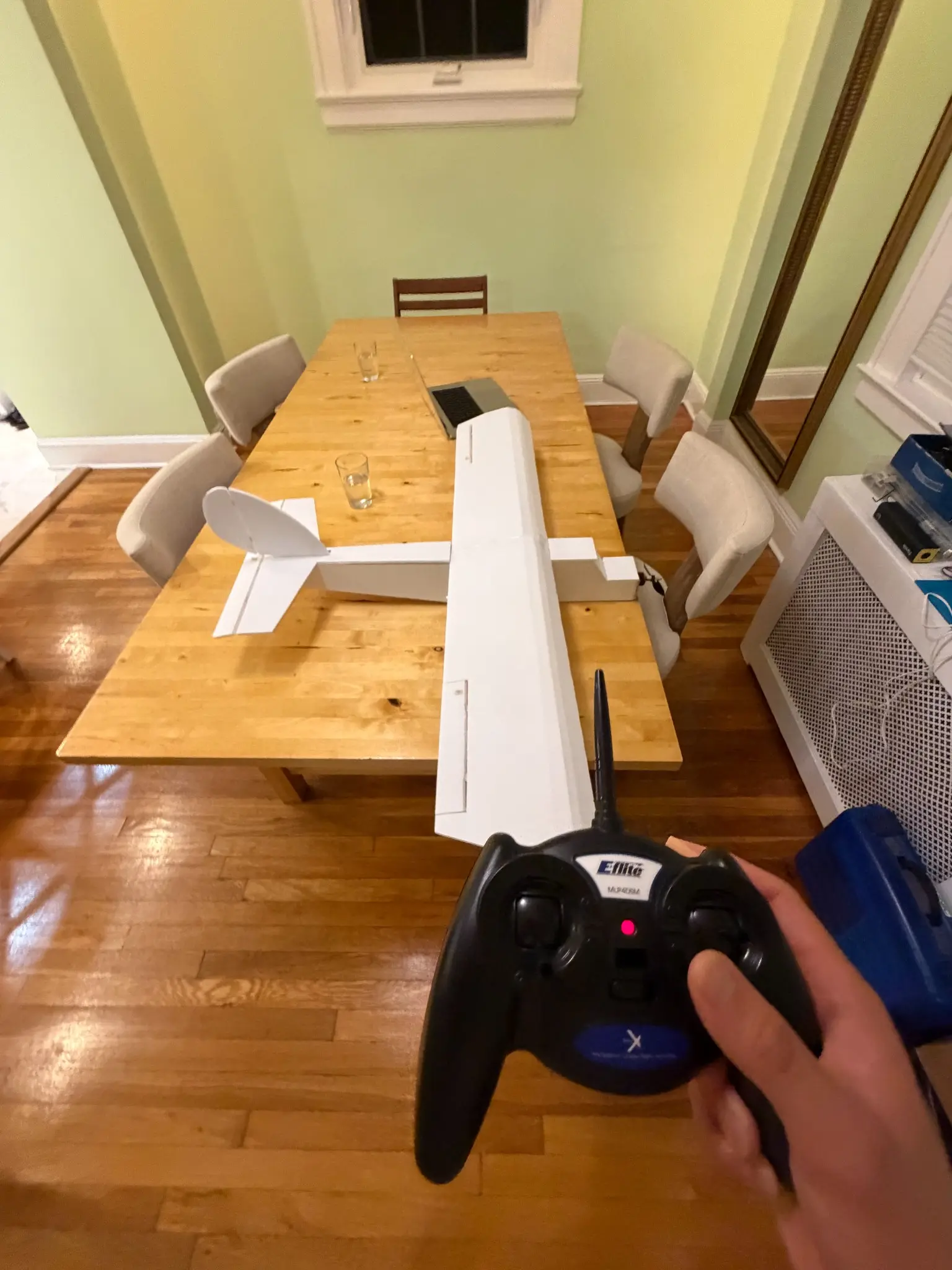 Completed RC aircraft on a table during a pre-flight control check with its transmitter.