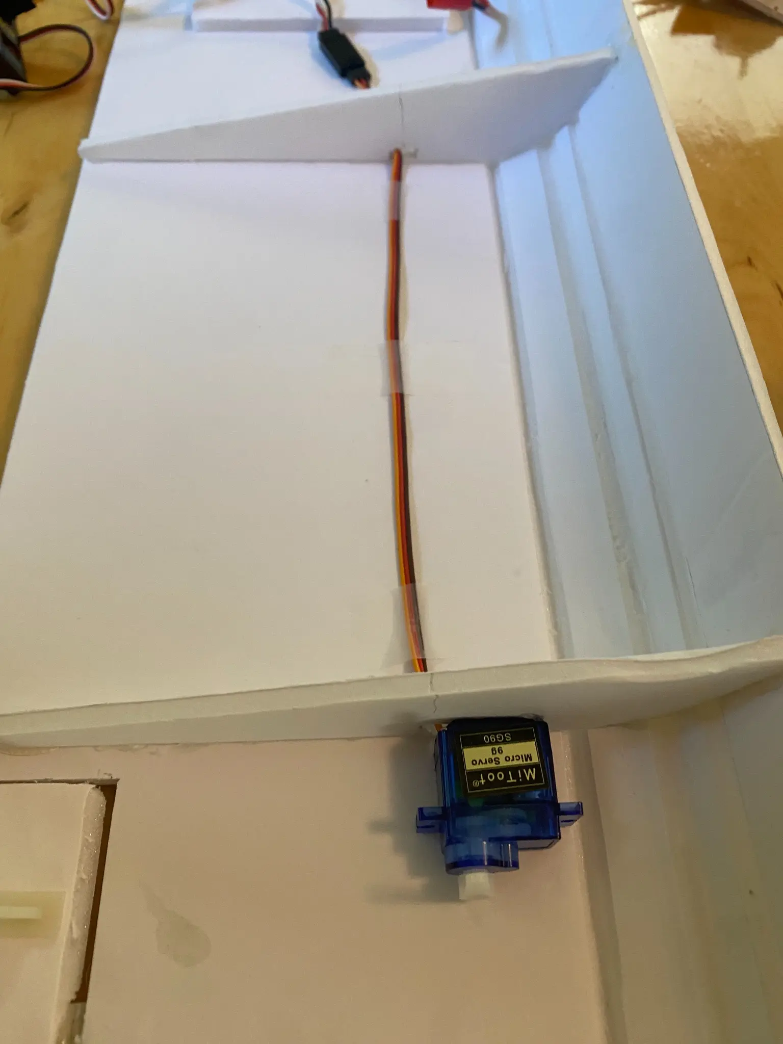 Small blue control servo mounted inside the foam-board wing structure.