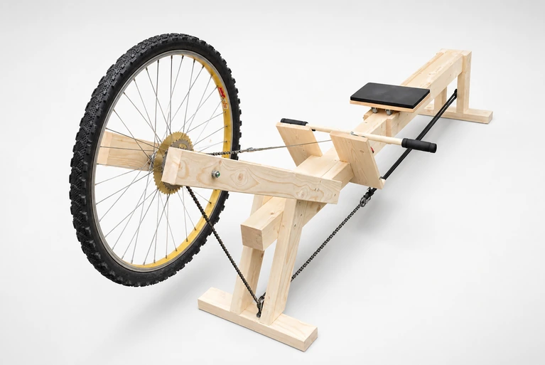 The DIY rowing machine, built with a wooden frame and repurposed bicycle wheel.